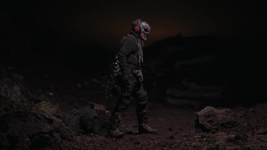 A masked figure wearing a dark tactical outfit with a weathered almost postapocalyptic look
