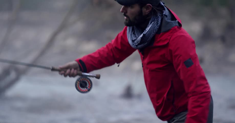 A man stands in a river and casts his fishing line