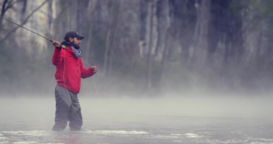 A man fly fishing by a pond or lake