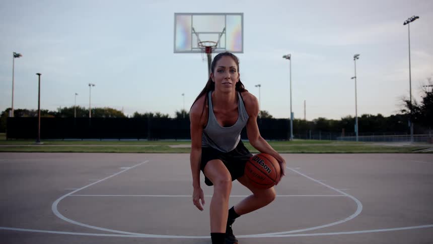 Woman on an open court dribbling a basketball