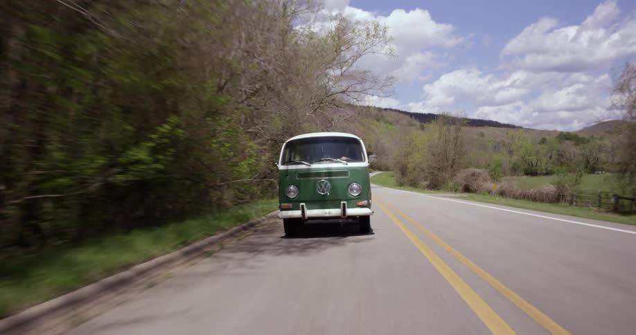 Classic van drives down a tree lined road