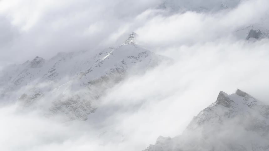 Clouds hover above a snowy mountain