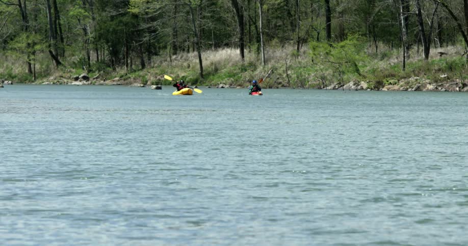Two kayakers paddling side-by-side on some calm water