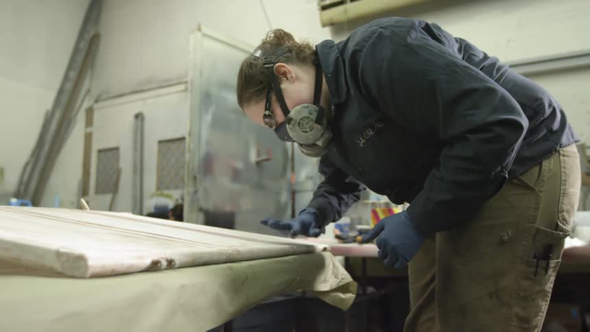 Woman smoothing a surface in a workshop