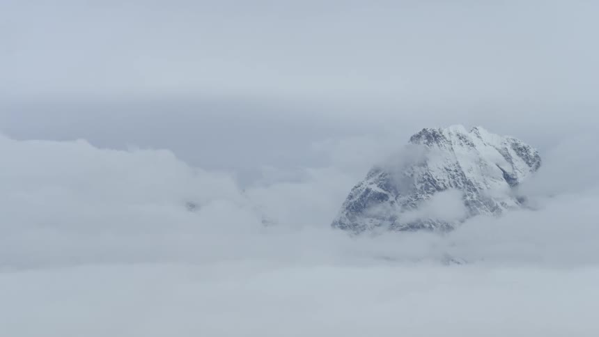 Snow-covered cap of a mountain as seen amongst the clouds
