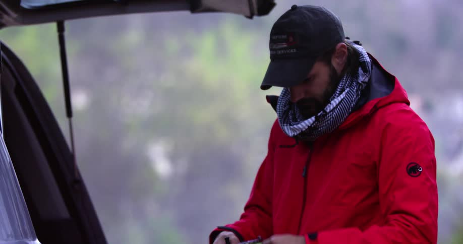 A man holding a reel of thread or string behind a truck