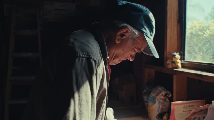 Elderly man working in an indoor space with some small wooden slats