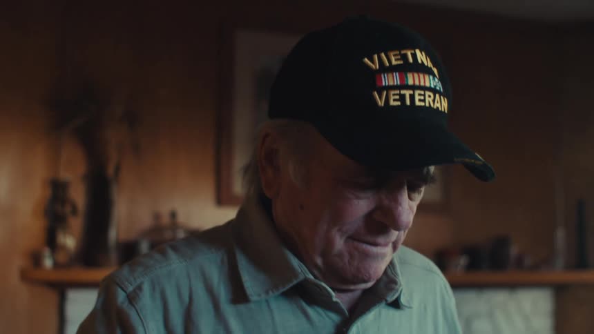 Vietnam veteran standing in his home examines a small american flag