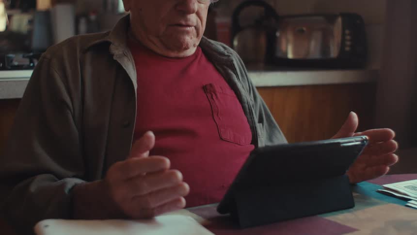 A clip of an elderly man having a conversation on a tablet