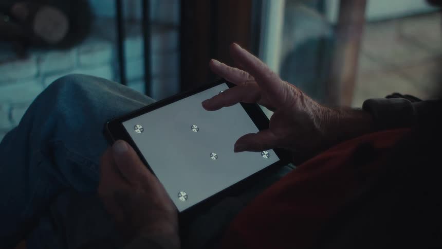 An old man attempts to use a tablet with a nonworking screen