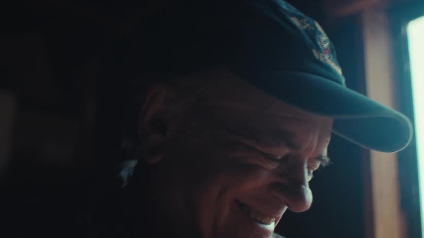 Elderly man wearing a cap in an indoor space giving a genuine smile