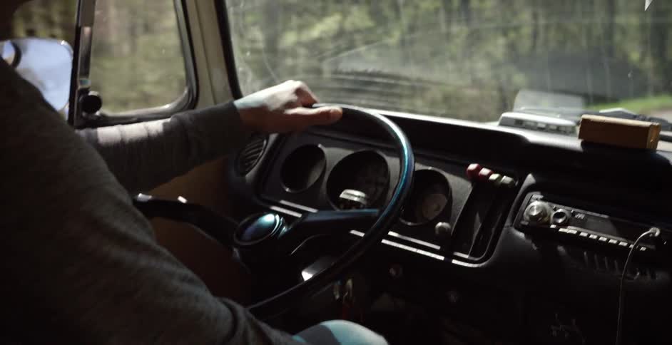 Person driving a moving vehicle as seen from just behind the driver's shoulder