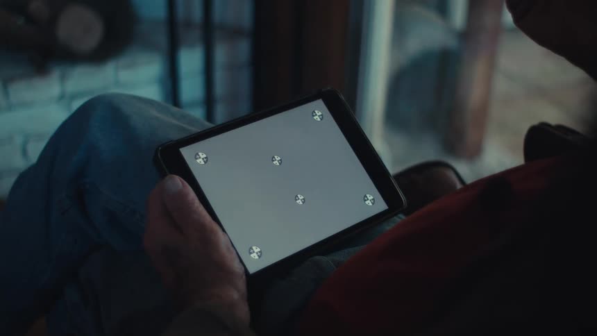 Elderly man sitting at home gestures while using a tablet