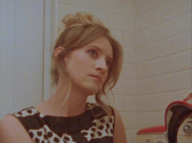 Portrait of a young blonde woman turning on an old radio