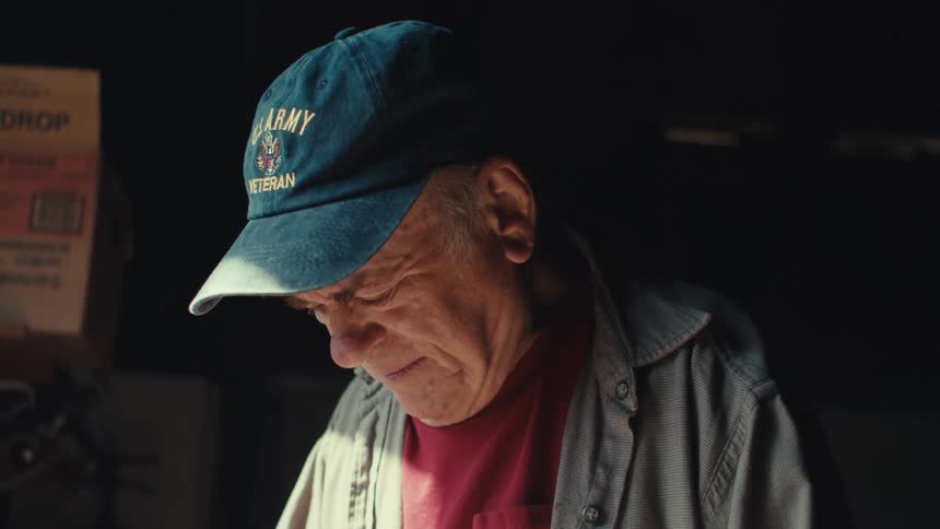 Elderly man in a blue cap looking down
