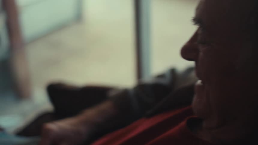 Elderly man sitting in living room and interacting with an iphone