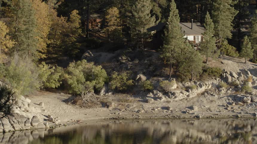 View of a cabin next to a lake in the forest