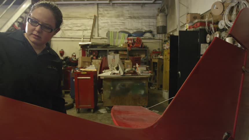 Woman rubs her hand on large object in a workshop