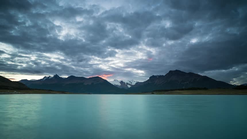 Landscape on a cloudy day of a blue lake with mountains in the background