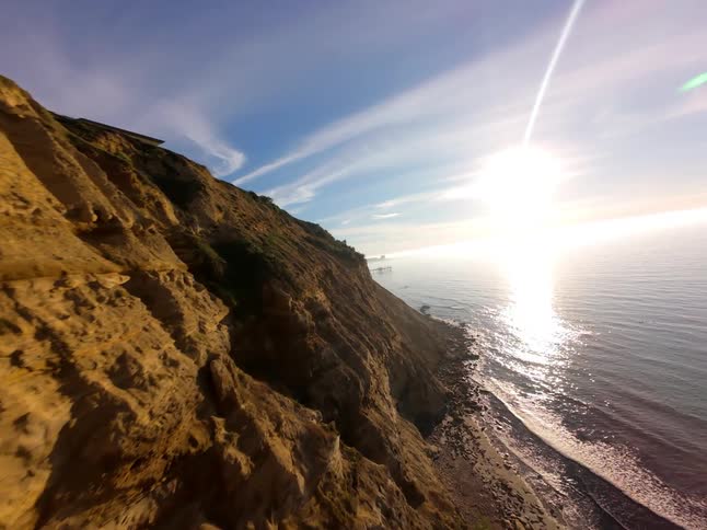Sparse structures populate a coastline with steep cliffs from the waters edge