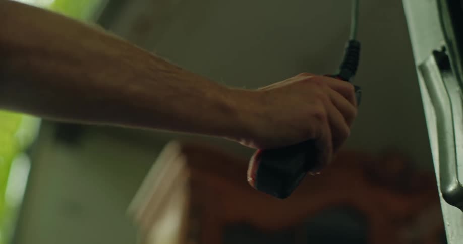 Hand holding a tool and using it on the outside of a truck