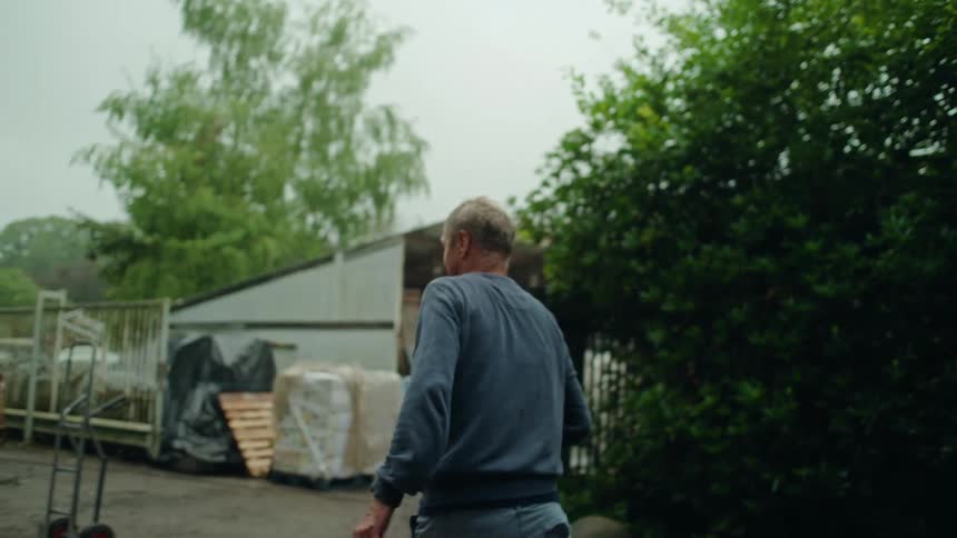Man in a backyard looking up and walking away