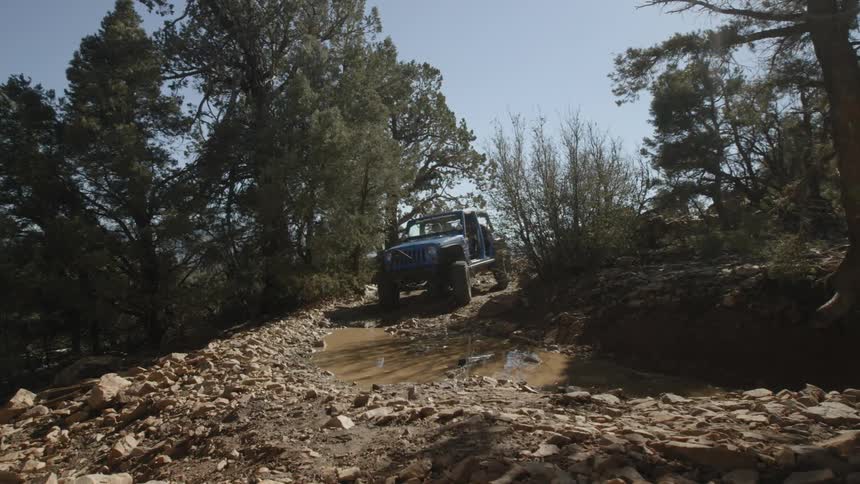 A jeep drives down a rocky road in the mountains