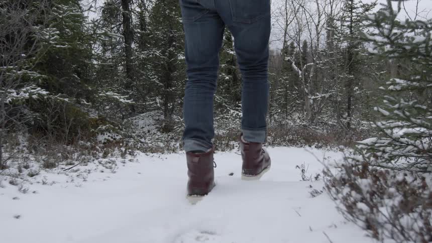 Person walking a snowy path as seen from the waist down