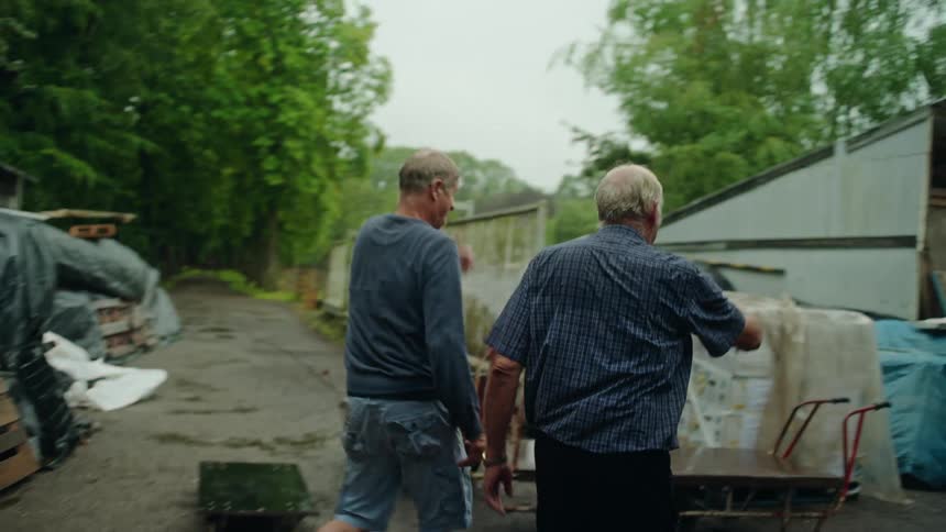 Three men walk towards the storage area of a lot