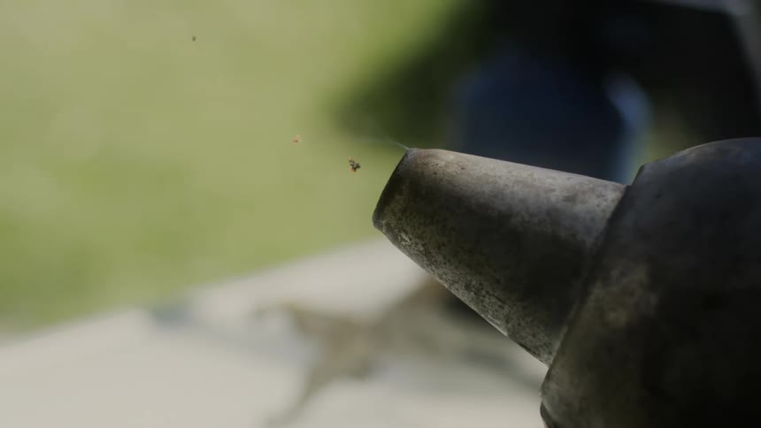 Various pieces of small debris shoot out of a metal spout