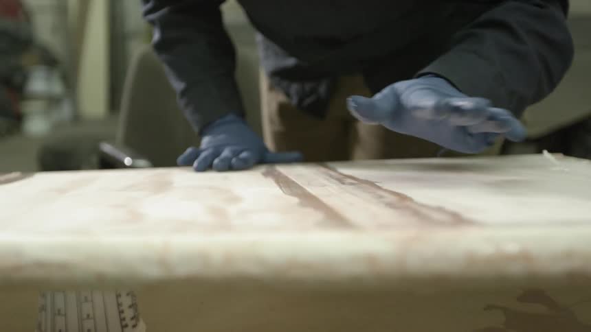 A person applies glue to a board