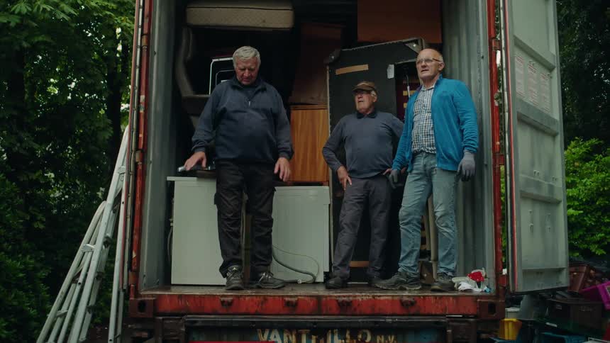 Three elderly men inside a moving truck