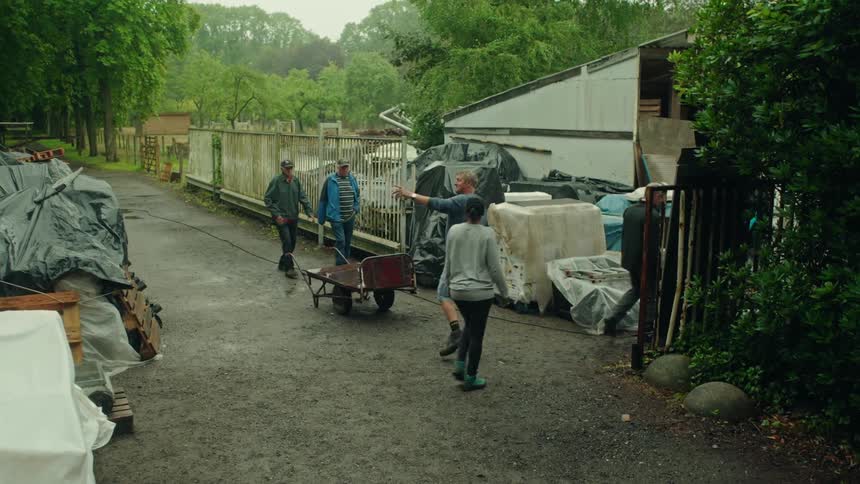 Man talks to two people while other workers walk through the worksite gate
