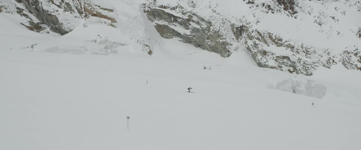 Aerial of a lone skier snow skiing down a long run in the mountains