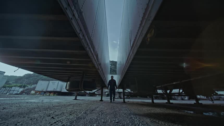 Man walks between two semi trailers supported by jack stands