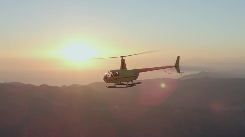 A helicopter flies near sunset