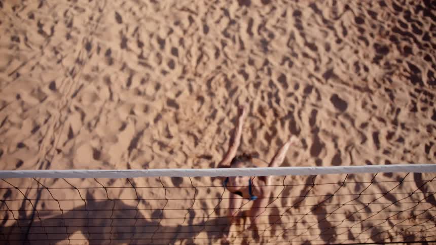 Top view of a woman playing volleyball on a sand court