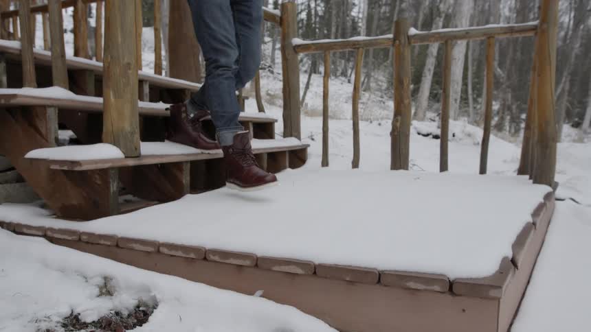 A man is walking down snowy stairs
