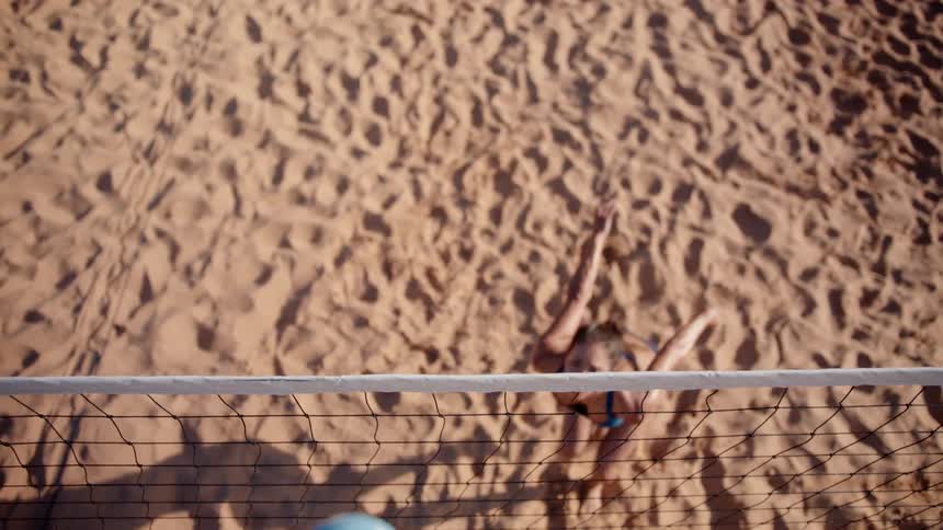 A woman jumps and hits the volleyball over the net