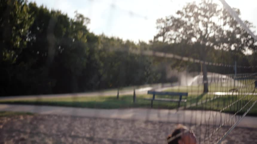 Woman on a sand volleyball court jumping and playing volleyball