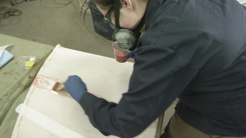 A woman wearing a mask is painting a liquid on a surface