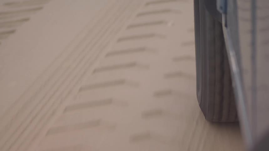 Front left tire view of a car driving on sandy soil