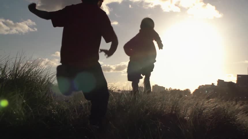 Children run in a grassy field