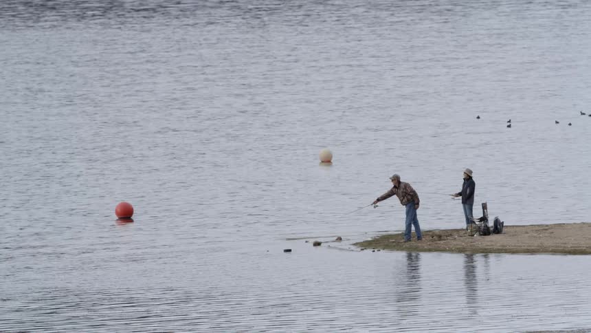 Man casting his fishing line into the water from the shore