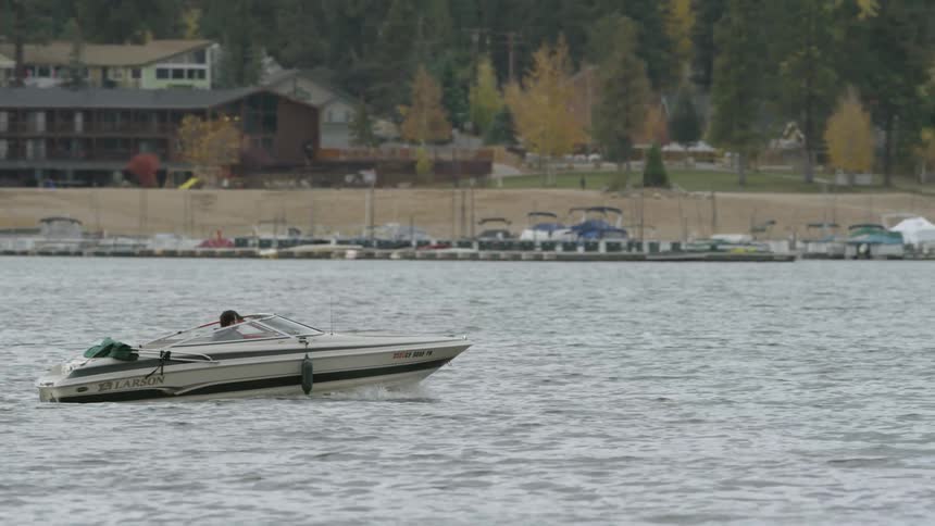 A boat driving on a river lined with boats and houses