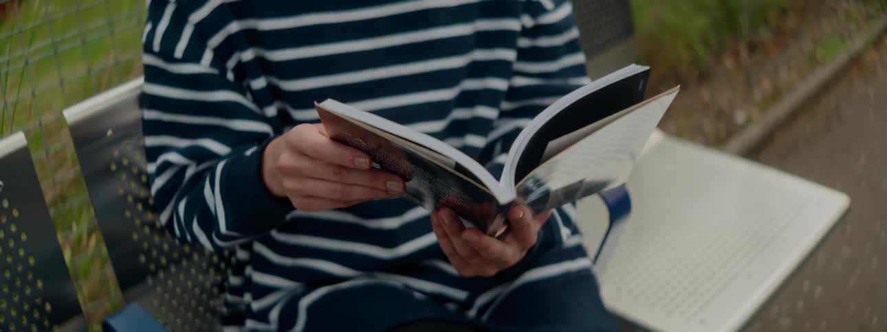 A clip of a person reading a book outdoor