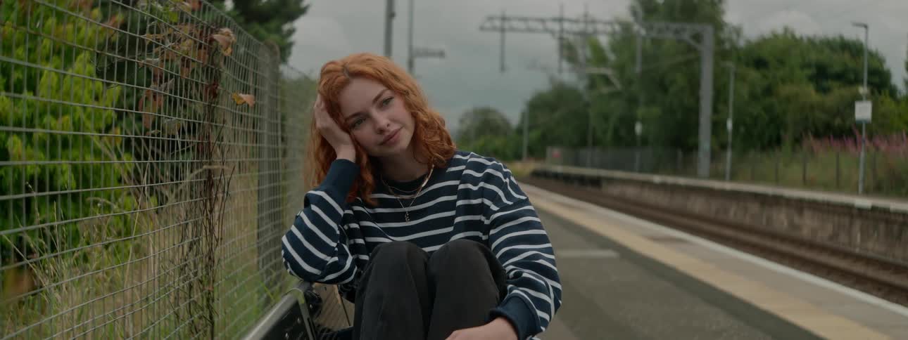 Redhead woman sitting on a bench thoughtfully