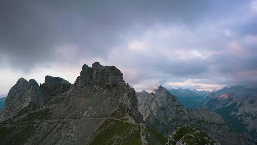 Clouds and mountainous terrain darken as the sun sets
