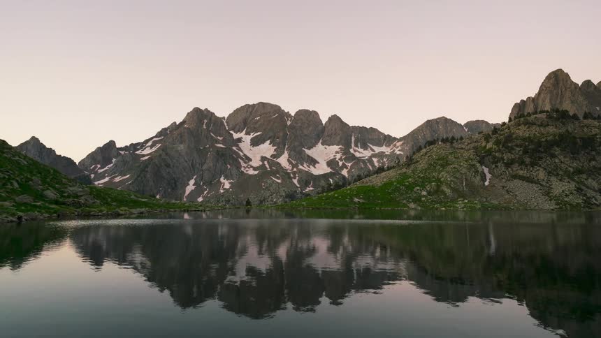 Landscape of a calm lake surrounded by snowy mountains and the day dawning