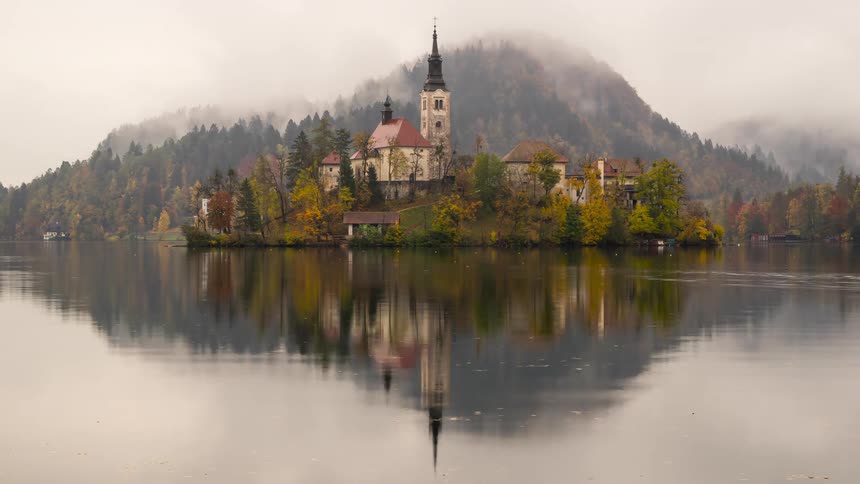 Landscape of an island with a picturesque town surrounded by a lake and forested mountains in the background